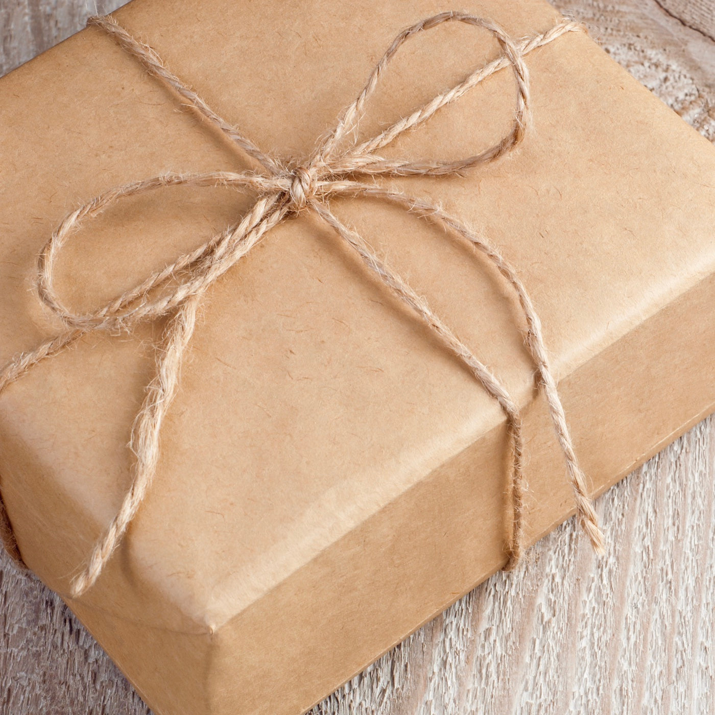gift box wrapped in brown paper with a rafia bow